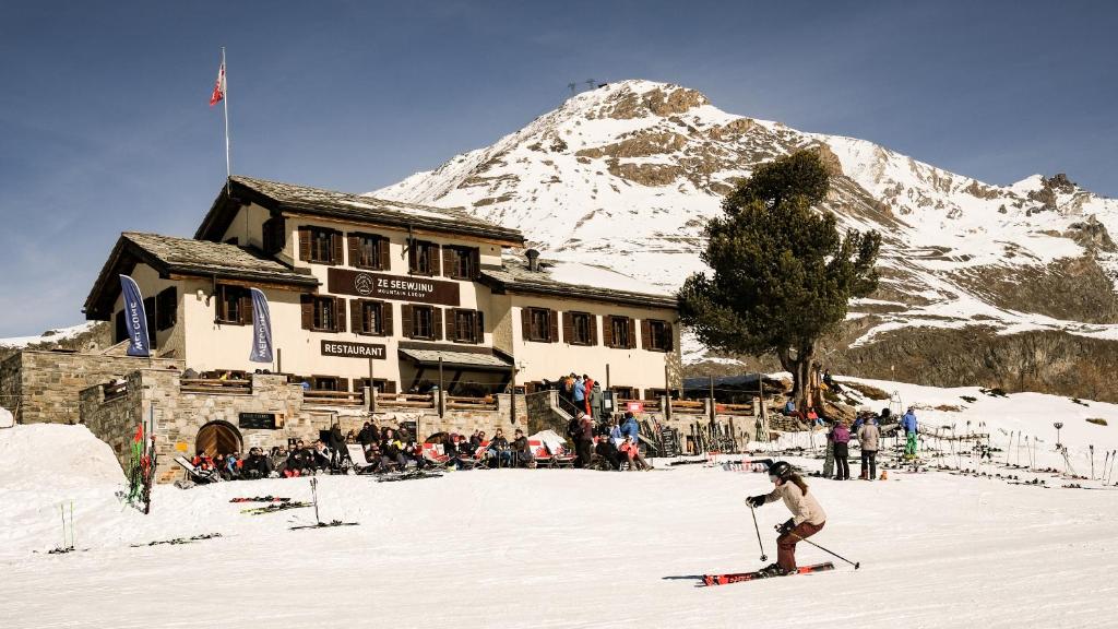 a person on skis in the snow in front of a ski lodge at Mountain Lodge Ze Seewjinu - above Zermatt in Zermatt