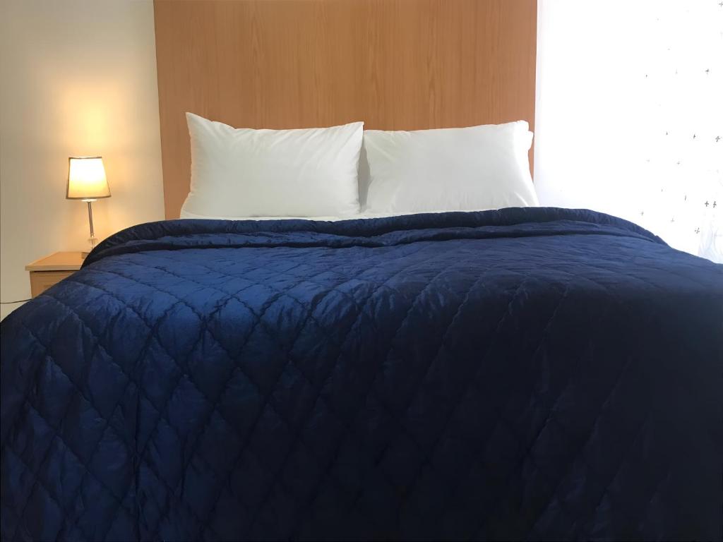 un letto con coperta blu e cuscini bianchi di The Plum a Louis Trichardt