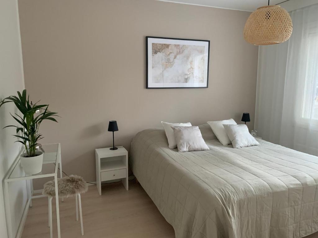 Dormitorio blanco con cama y maceta en 3 h + keittiö ja parveke, juuri remontoitu!, en Lahti