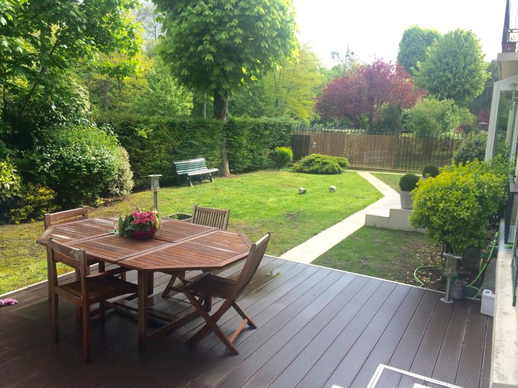 - une terrasse en bois avec une table et des chaises sur la cour dans l'établissement Un air de campagne à Paris, à Saint-Maurice