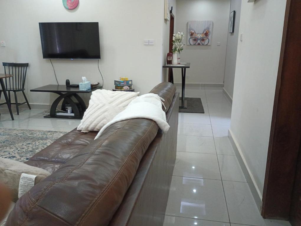 a brown leather couch in a living room with a tv at Himma's Apartments 