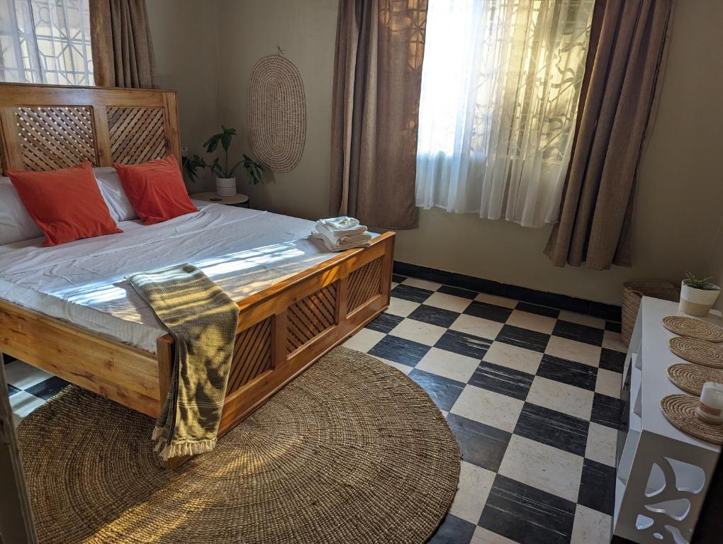 um quarto com uma cama de madeira e almofadas vermelhas em The Lion King Homestay em Moshi