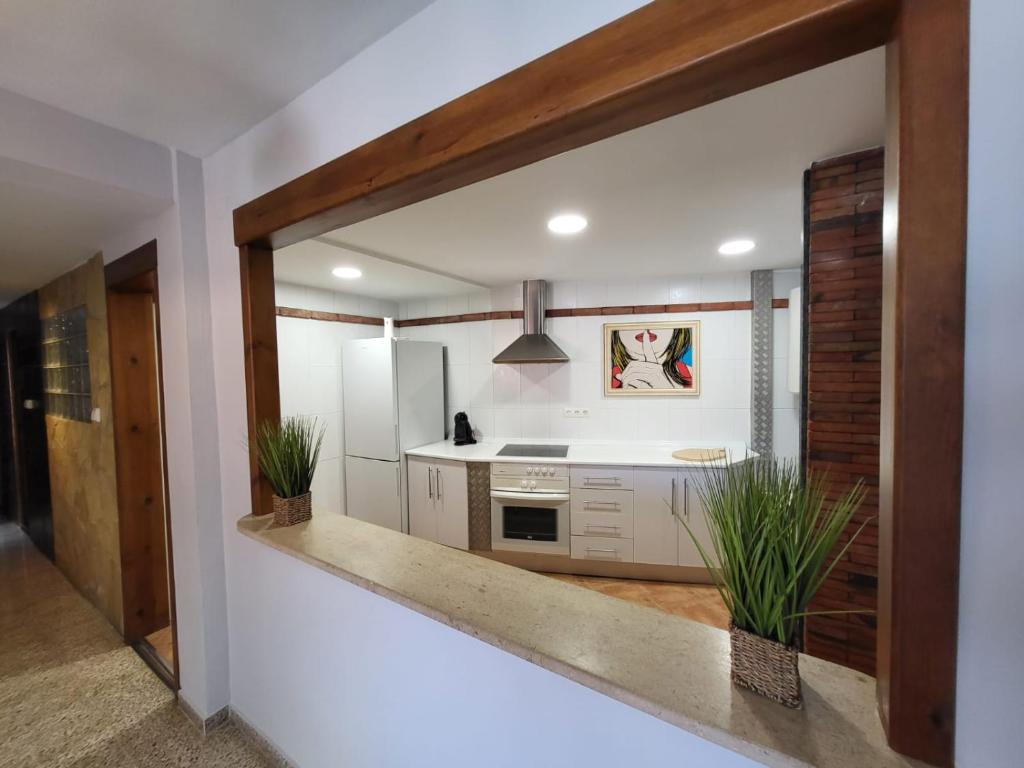 uma cozinha com armários brancos e um balcão com vasos de plantas em Motril centro. em Motril