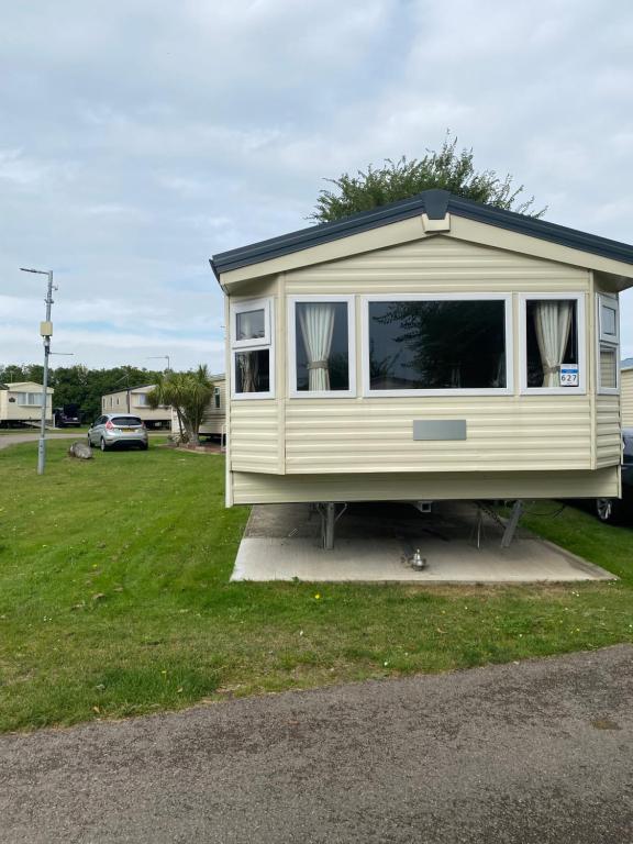 a small yellow tiny house sitting on a grass field at Holiday home at Parkdean Cherry Tree Holiday Park 627 in Great Yarmouth