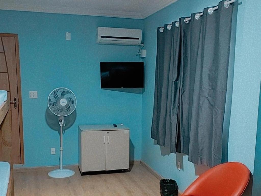 a room with a fan and a blue wall at Pousada Califor in Nova Iguaçu