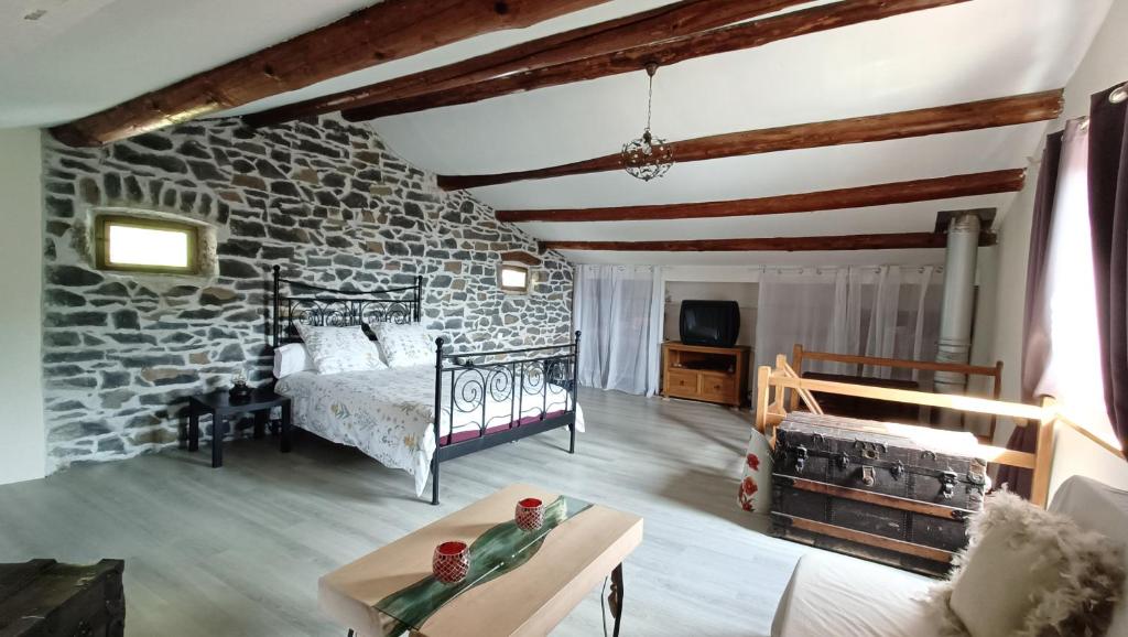 a bedroom with a bed and a stone wall at Le Carpé Diem in Saint-Privat-dʼAllier