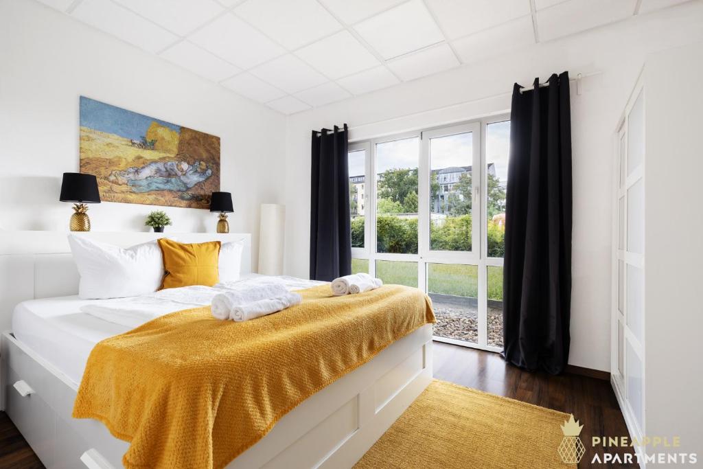 a white bedroom with a bed with a yellow blanket at Pineapple Apartments Dresden Mitte - free parking in Dresden