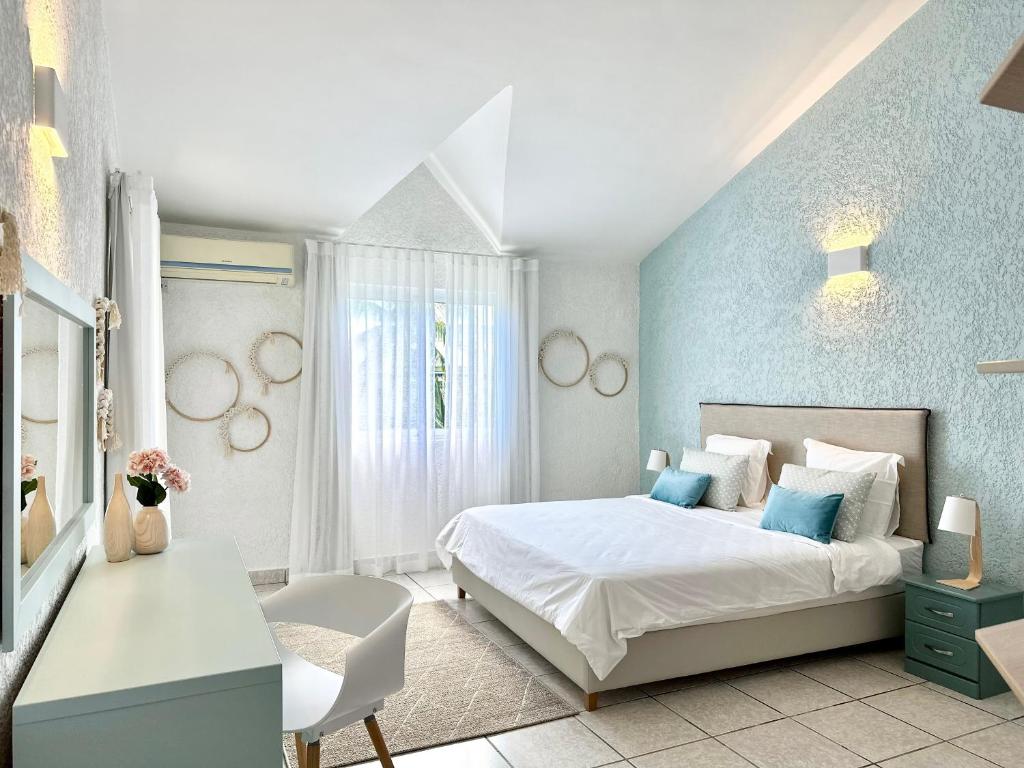 sypialnia z białym łóżkiem i niebieską ścianą w obiekcie Azur - Résidence Le Dattier w mieście Flic-en-Flac