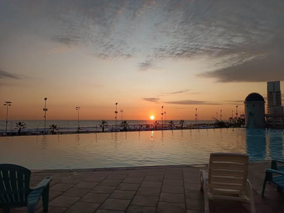 a pool of water with two chairs and a sunset at Luminoso depto 3 dormitorios 2 baños frente al mar in Iquique