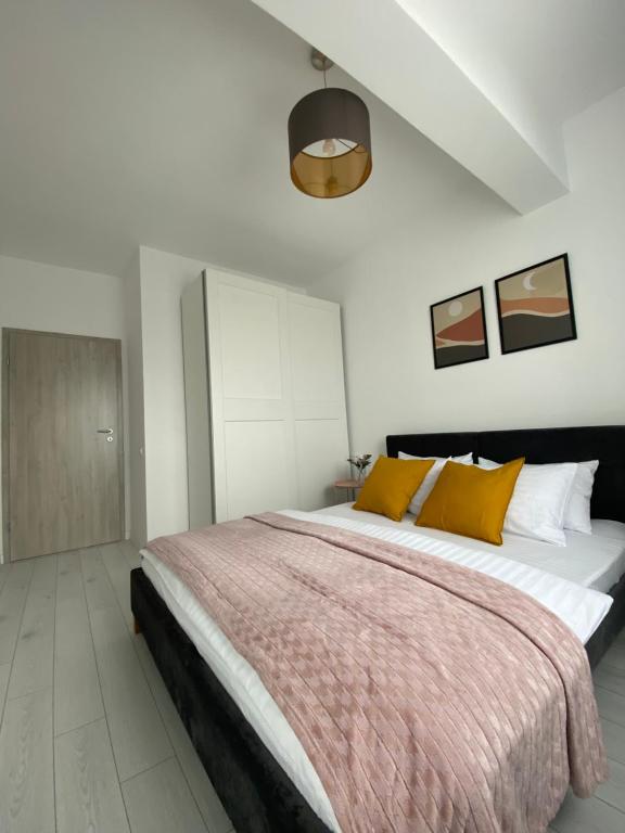 1 dormitorio con 1 cama grande con almohadas amarillas en Orhideea Central Apartments, en Bucarest