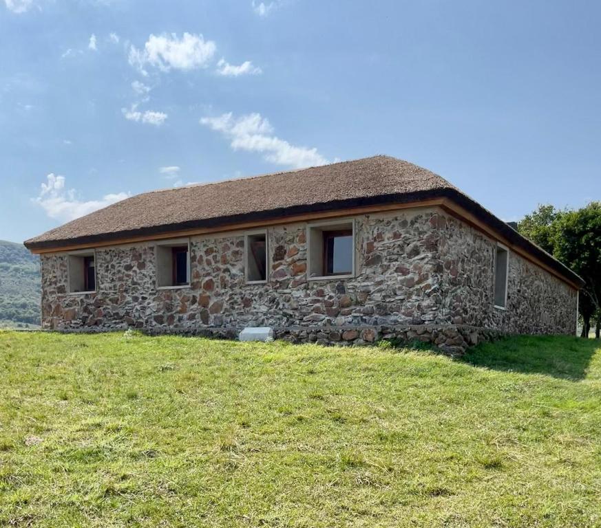 uma casa de pedra no topo de uma colina relvada em Casa de campo em Rivera