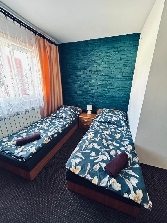 a bedroom with two beds and a blue wall at Zajazd Kasieńka pokój 2 in Orzysz
