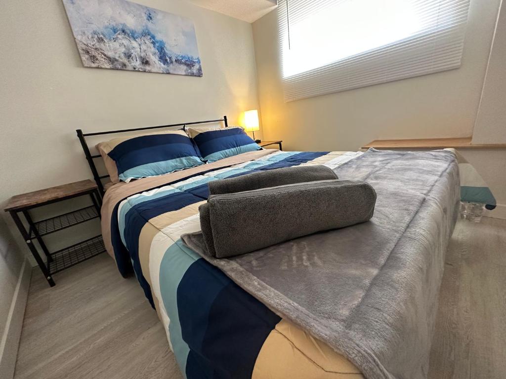 a bedroom with a bed with blue pillows and a window at Comfy 2 Bedroom Near The Beach! in Pickering