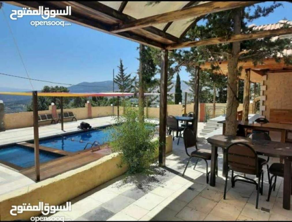 a patio with a table and chairs and a swimming pool at Raghad Chalet in Jerash