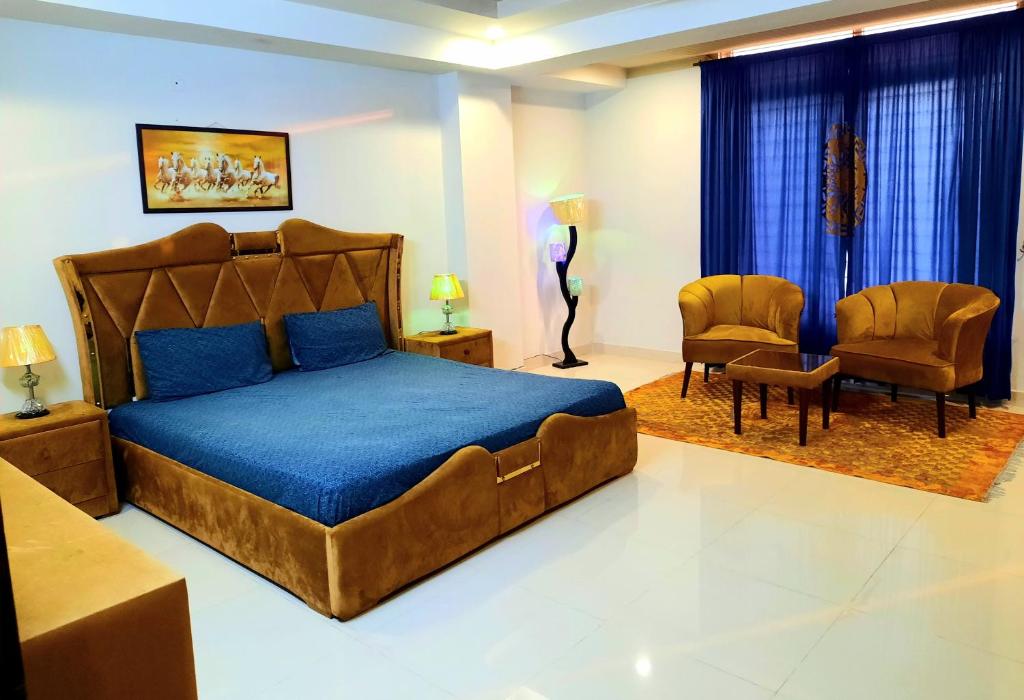 a bedroom with a large bed and two chairs at Anabi Apartments and Suits E11 Islamabad in Islamabad
