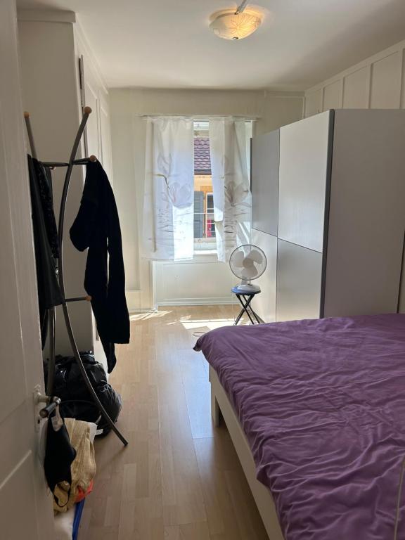 1 dormitorio con cama morada y ventana en Maison Merz, en La Neuveville