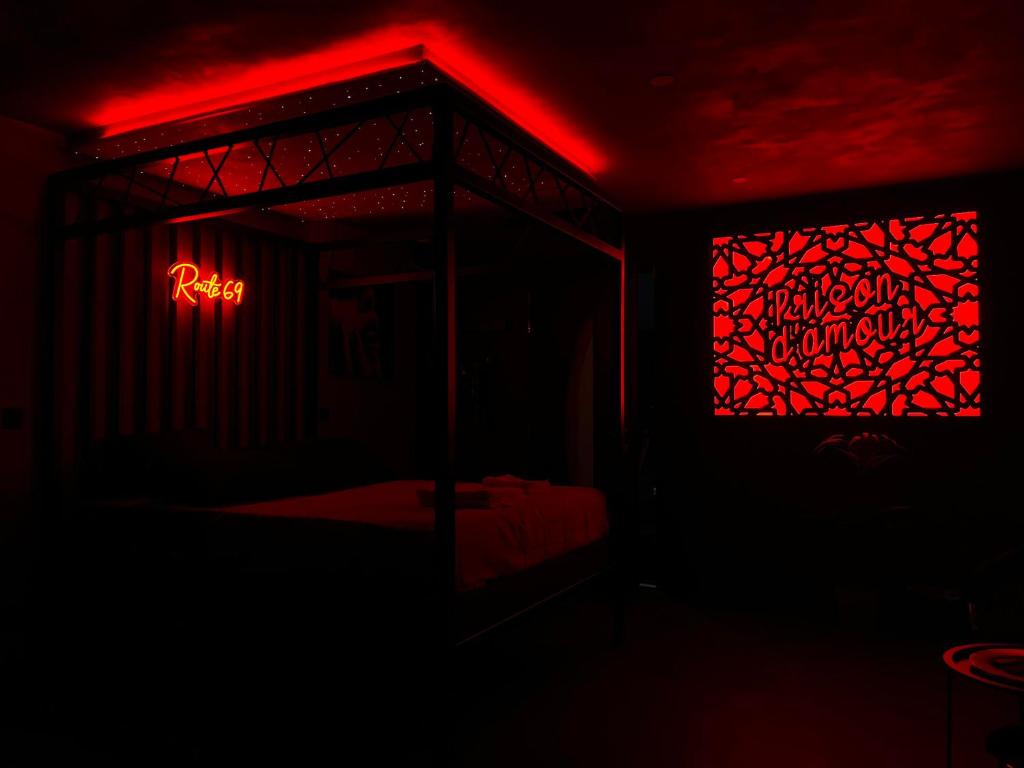 a dark room with a bed and a red light at Chambre Romantique avec Jacuzzi R in Gruny