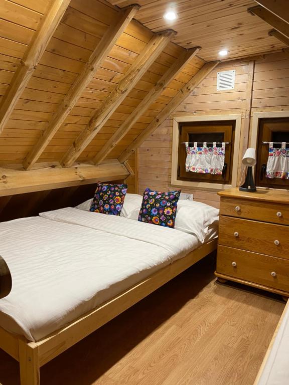 duże łóżko w pokoju z drewnianymi sufitami w obiekcie Verde Land - Drewniany domek na wsi w mieście Osiek Mały