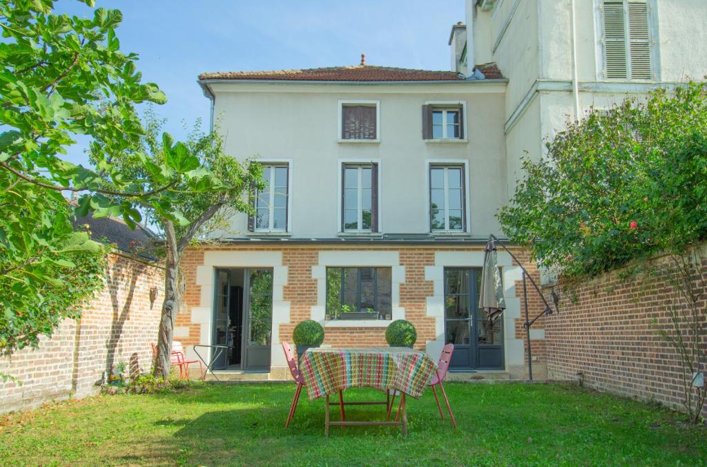 una mesa y sillas frente a una casa en Le Cordelier - Jardin en plein centre - Quais de Seine, en Troyes