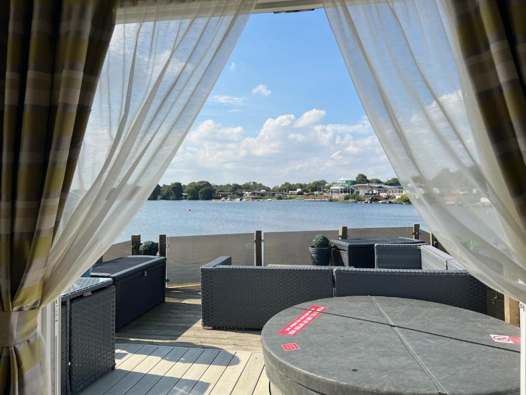 a patio with a table and a view of the water at Lake View with Private Hot Tub at Tattershall Lakes in Tattershall