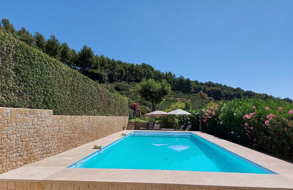 uma piscina num jardim com uma parede de pedra em Mas Chamarel, la Provence entre vignes et oliviers proche de la mer em Sanary-sur-Mer