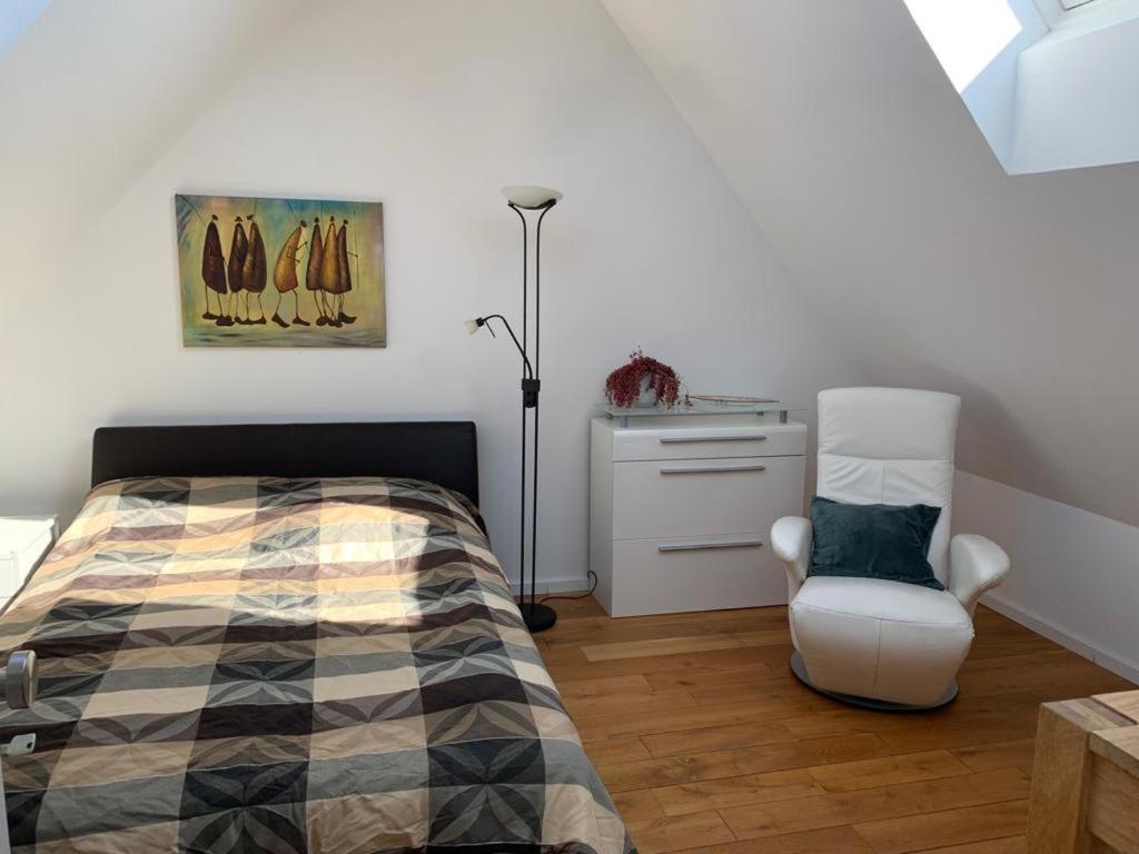ein Schlafzimmer mit einem Bett und einem Stuhl in der Unterkunft Dachwohnung Nähe Clemenshospital in Münster