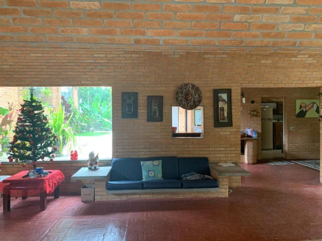 Sítio em Itapecerica da serra في إتابيسيريكا دا سيرا: غرفة معيشة مع أريكة زرقاء في جدار من الطوب