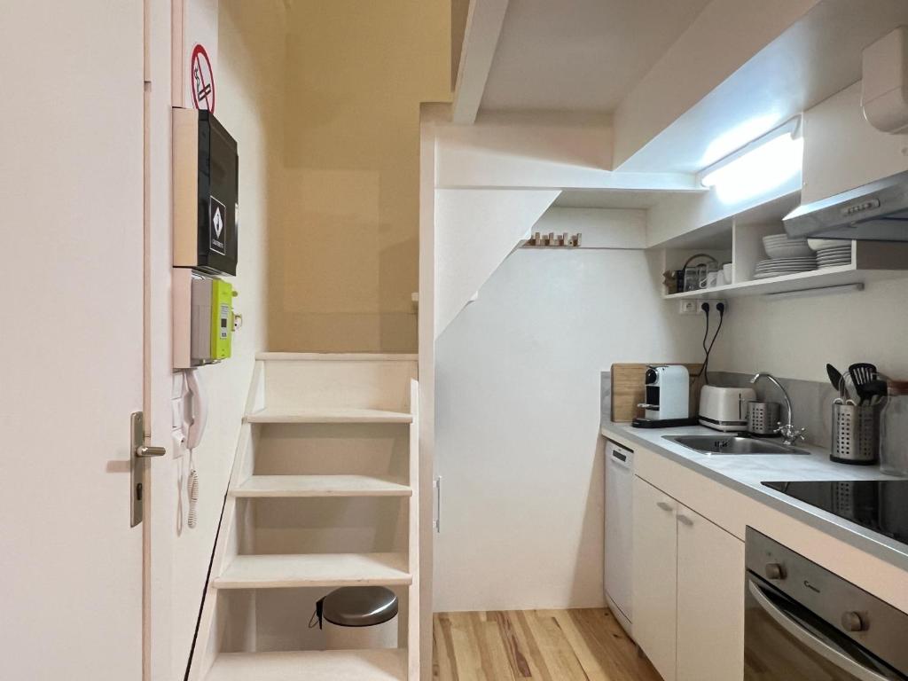 a small kitchen with white cabinets and a staircase at Joli studio + mezzanine 2-3 Pers in Cauterets