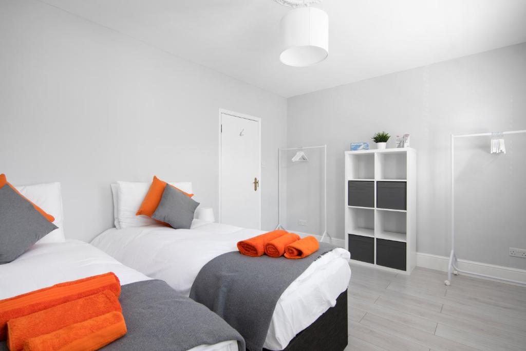 a bedroom with two beds with orange pillows on them at Cloud9 Accommodation 3-Bed Home in Croydon, Guest 6 - High Speed Wi-Fi in Croydon