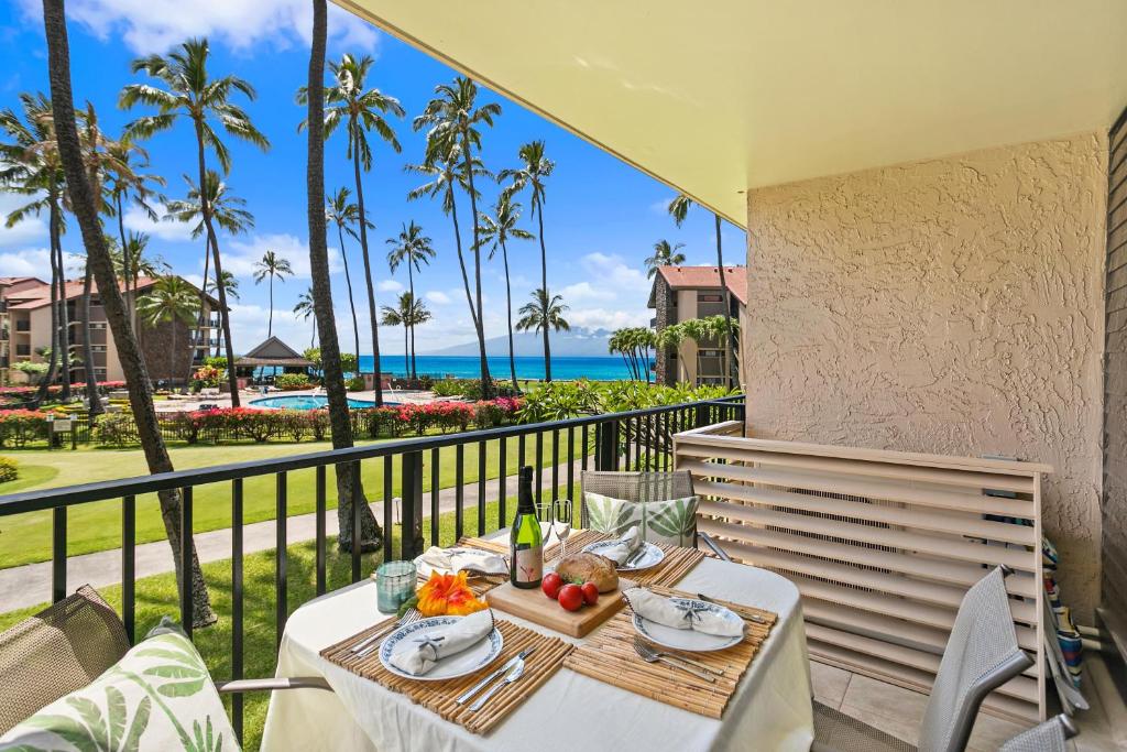 a table with food on a balcony with a view of the ocean at Papakea B201 in Kahana