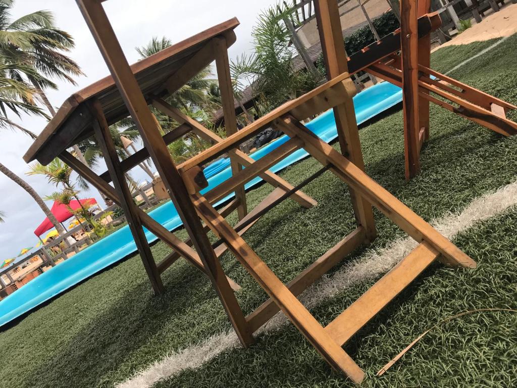 a wooden bench on the grass next to a pool at Pousada França in Japaratinga