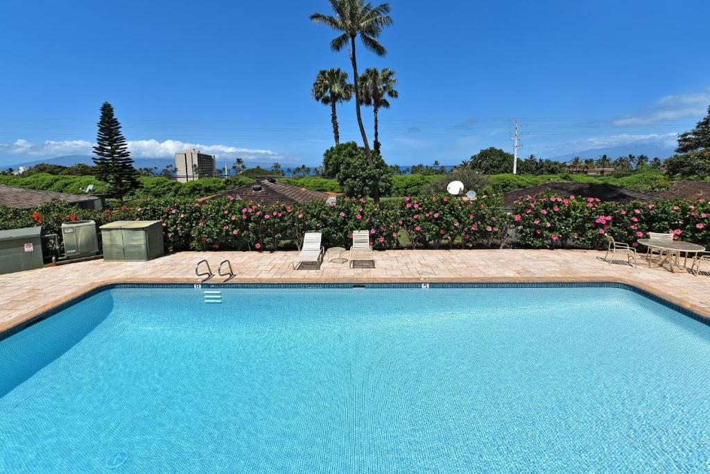 a large swimming pool in a yard with flowers at International Colony Club 34 in Lahaina