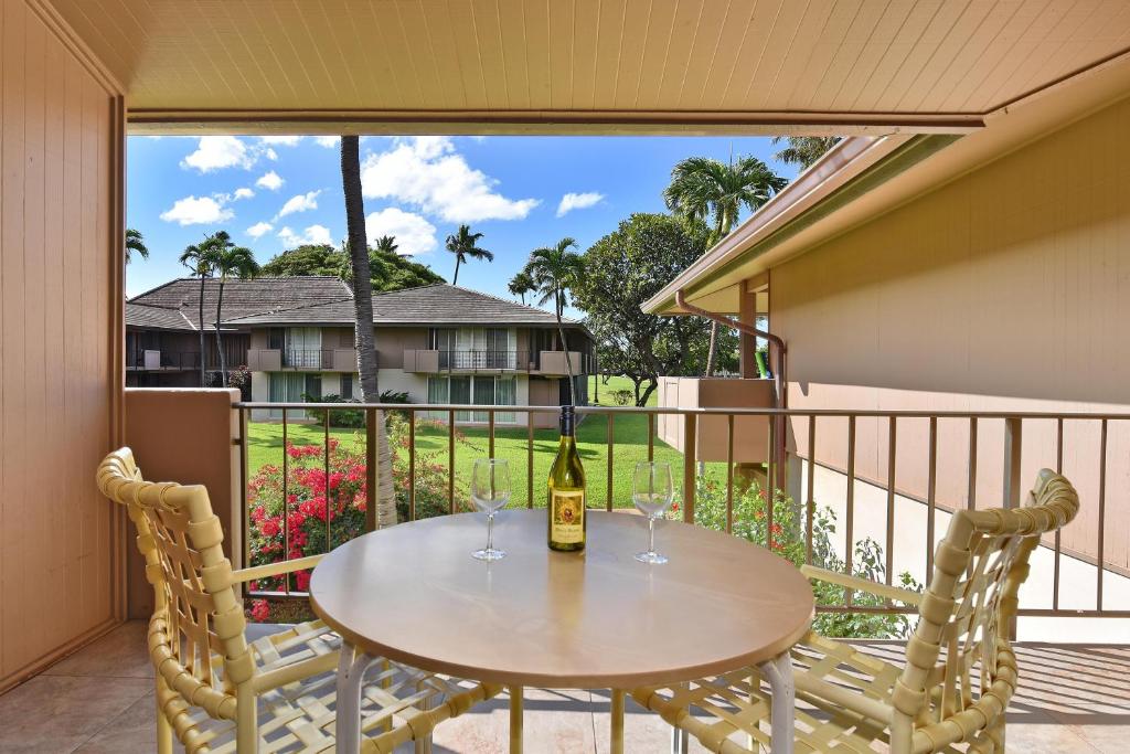 a table and chairs on a balcony with a bottle of wine at Eldorado J209 in Kahana
