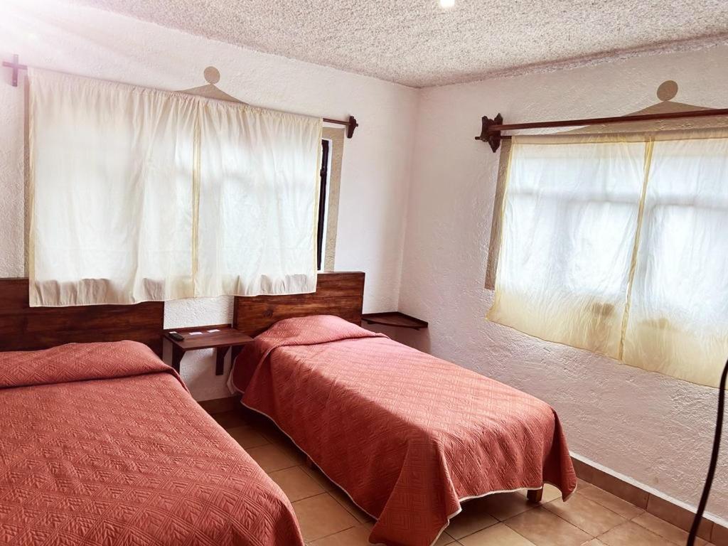 1 dormitorio con 2 camas y ventana en Azomalli en Tepoztlán