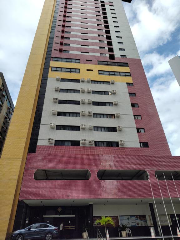 un edificio alto con un coche aparcado delante de él en BOA VIAGEM FLATS APTO 201, en Recife