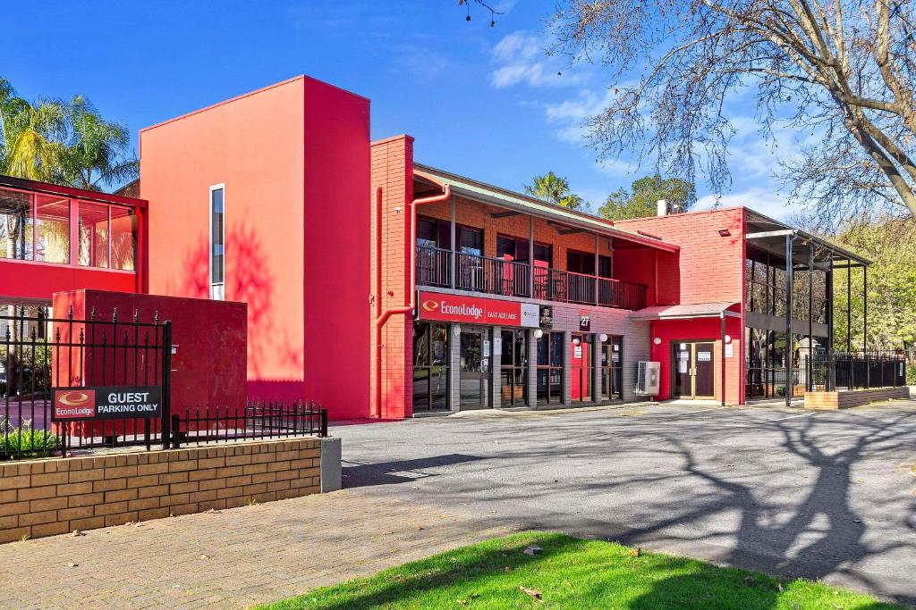un edificio rojo con un estacionamiento delante de él en Econo Lodge East Adelaide en Adelaida