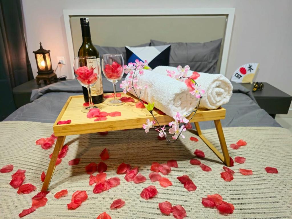 アンパンにある1 Dream Home @ Liberty Arc Studio 新时代日本风享受阳台吉隆玻夜景のベッドの上にワイングラスと花を添えたテーブル