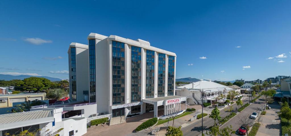 a large white building with blue windows on a street at Rydges Southbank Townsville in Townsville