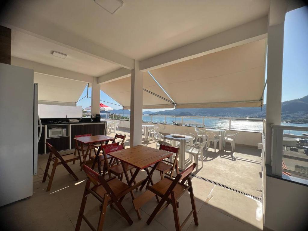 una cucina e una sala da pranzo con tavoli e sedie sul balcone di Suítes com Vista para o Mar no Marinas - Mirante do Marinas ad Angra dos Reis