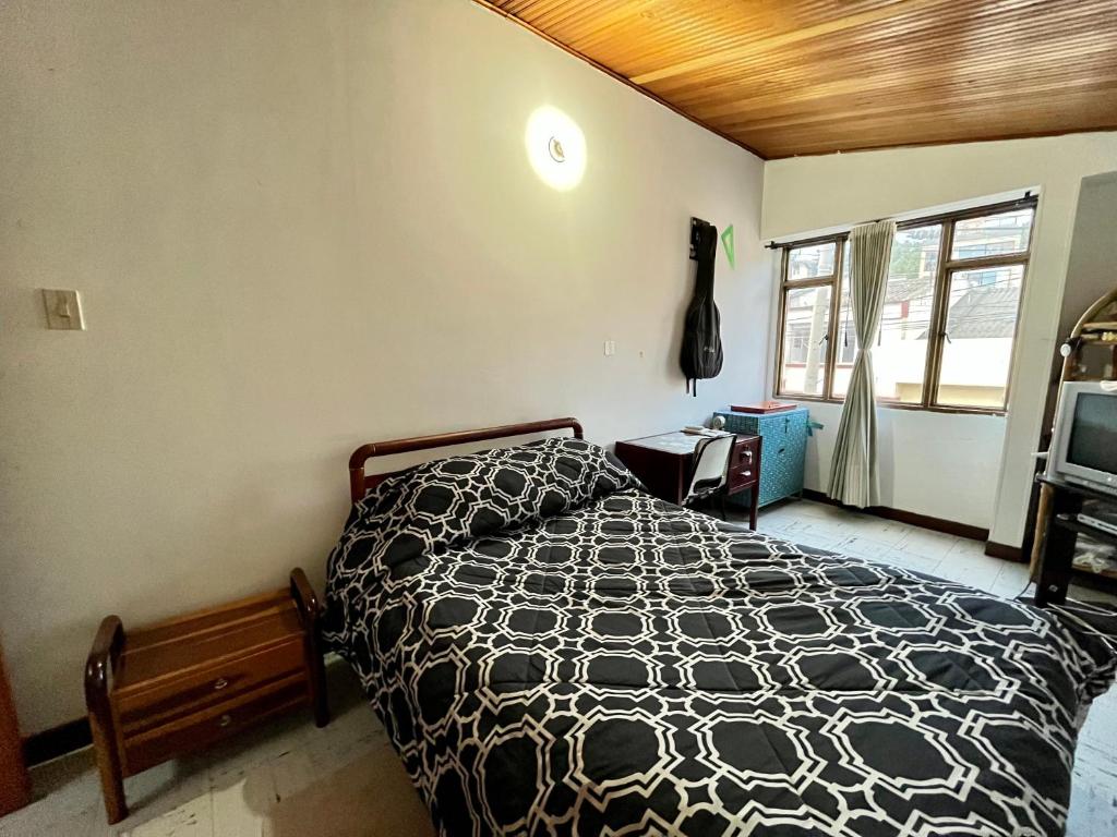 1 dormitorio con 1 cama con edredón blanco y negro en CASA FAMILIAR CENTRICA, en Duitama