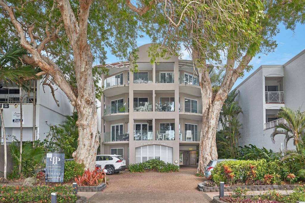 ein Mehrfamilienhaus mit Bäumen davor in der Unterkunft Coral Horizons Ocean View Apartments in Palm Cove