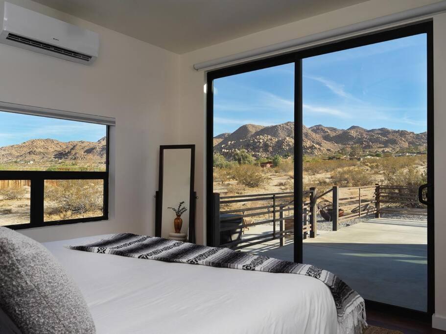 a bedroom with a bed and large glass windows at Panoramic Heaven - Luxury Designer Property w Spa in Joshua Tree
