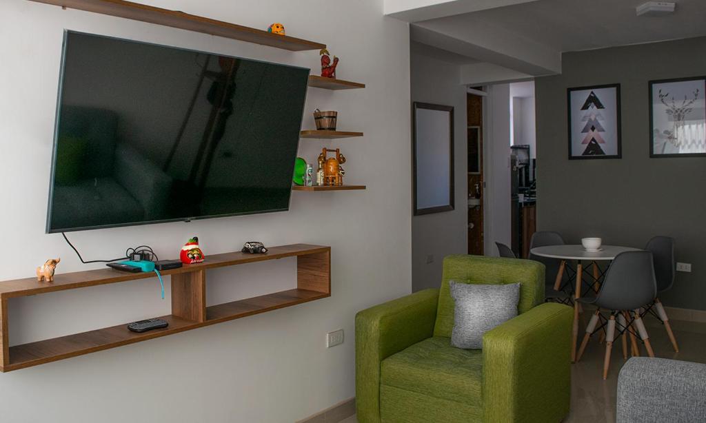 sala de estar con silla verde y TV de pantalla plana en Morada en Tacna