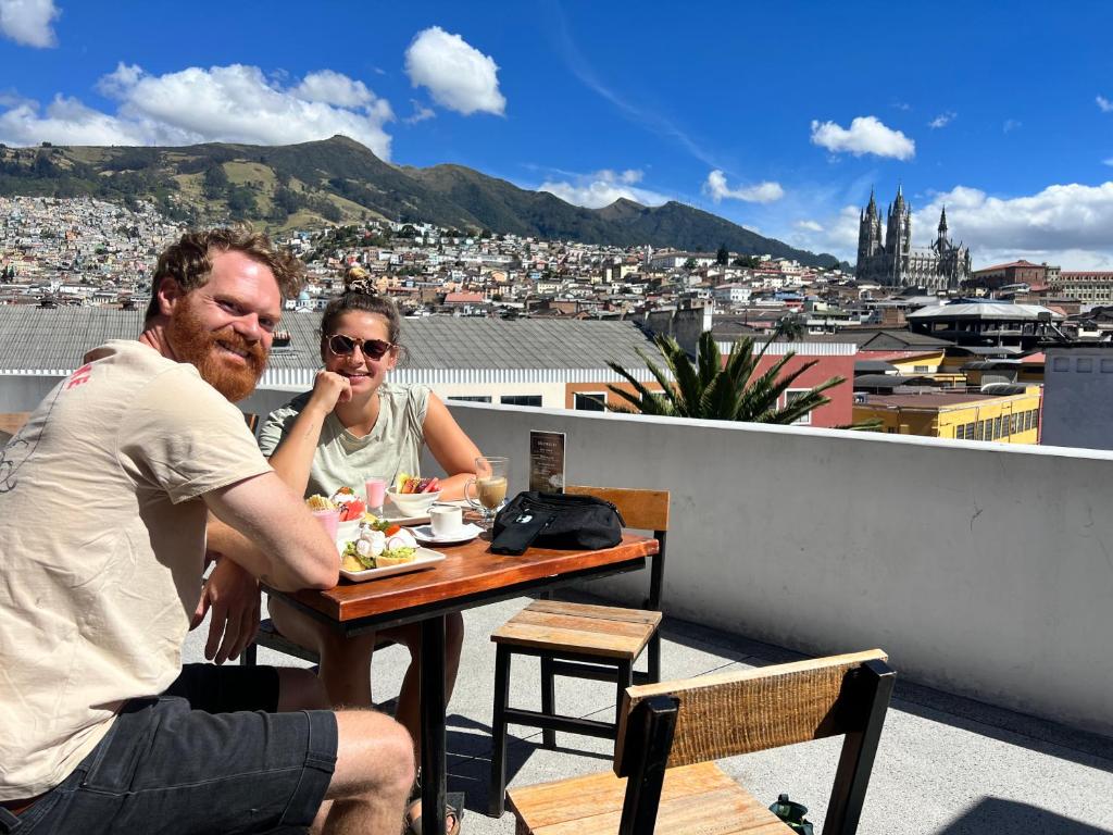 un hombre y una mujer sentados en una mesa en un techo en Community Hostel Quito en Quito