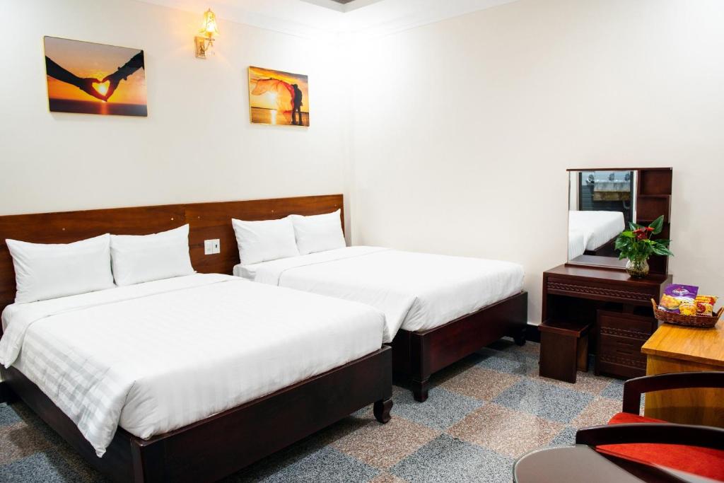 a hotel room with two beds and a desk at MINH LÂM HOTEL in Pleiku