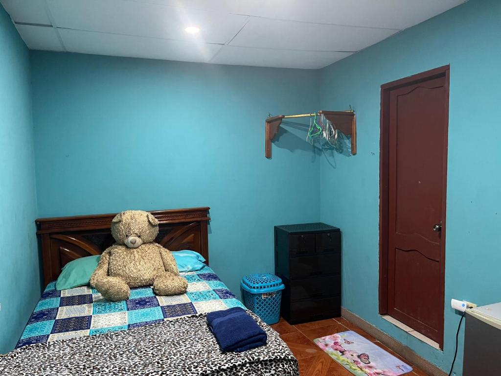 un osito de peluche sentado en una cama en un dormitorio en Casa Hogar Martita, en Puerto Baquerizo Moreno