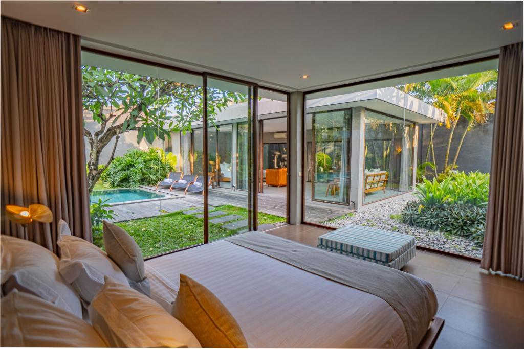 een slaapkamer met een groot bed en grote glazen ramen bij Ziva a Boutique Villa in Seminyak