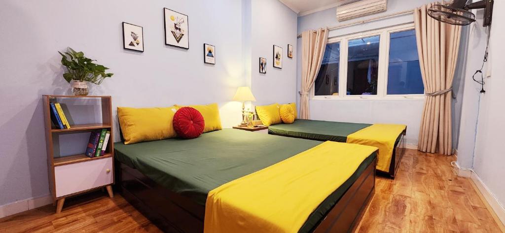 two beds with yellow and green sheets in a room at Hanoi Sunrise Homestay Long Biên in Hanoi