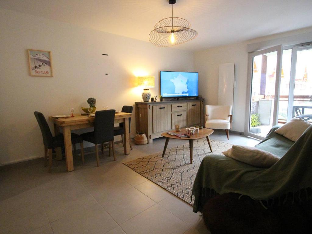 un salon avec un canapé, une table et une télévision dans l'établissement Appartement Cozy 3P avec Balcon Sud, Garage et Proche Golf - Montauban-de-Luchon - FR-1-313-227, à Montauban-de-Luchon
