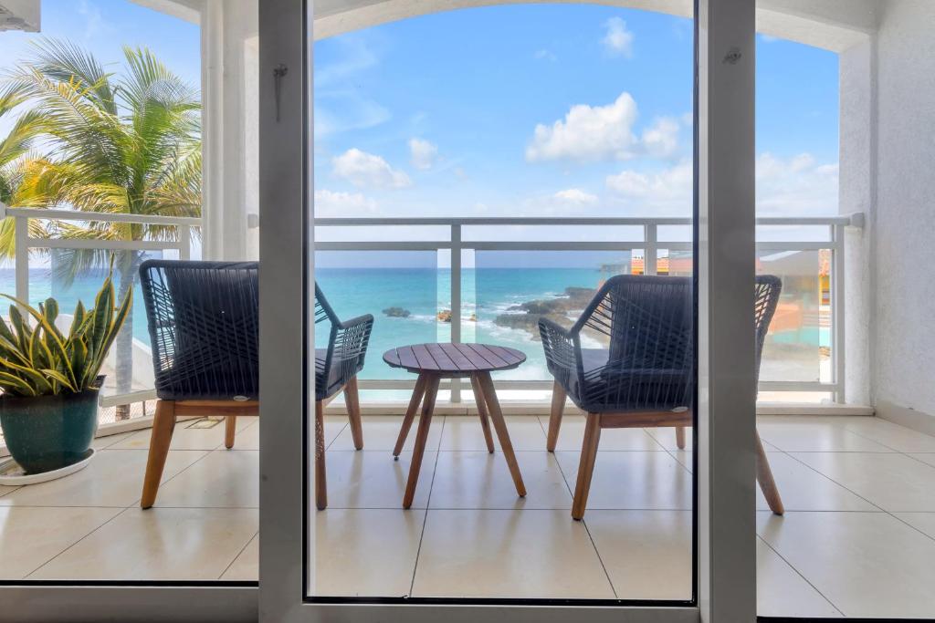 a balcony with a table and chairs and the ocean at Sand Bar Cove - Beach Bar Studio next to The Morgan Resort in Maho Reef